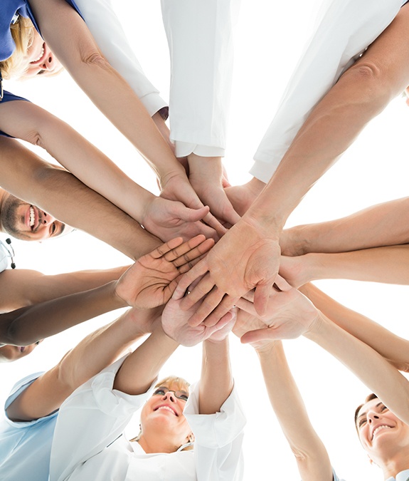 group of people putting hands into middle of circle