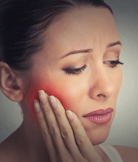 Woman holding cheek in pain before gum disease treatment