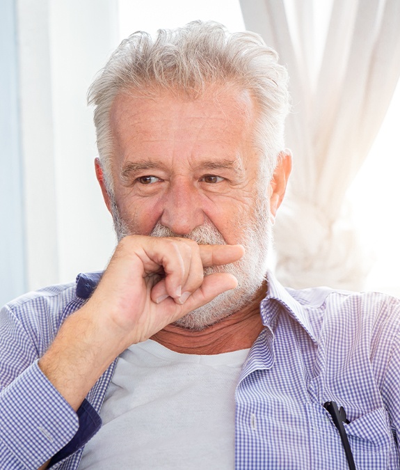Older man in need of periodontal therapy covering his mouth