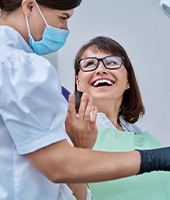 Woman smiling with dentist while reviewing X-ray