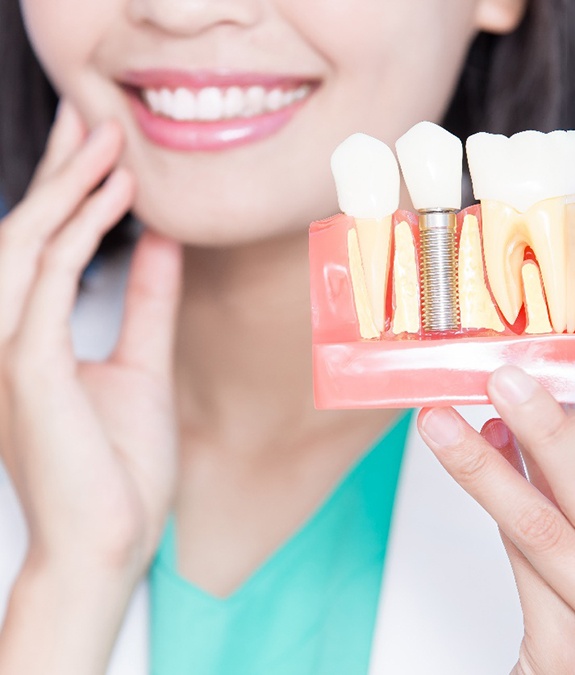 A dentist holding a mockup of a dental implant