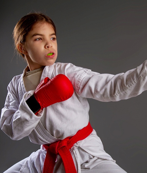 A young girl wearing boxing attire and a custom mouthguard