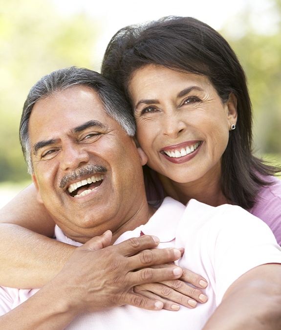 wife hugging husband while both laugh after dental crown restoration