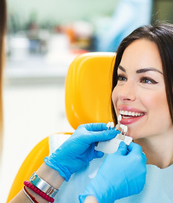 Dentist helping smiling patient select shade of dental crown
