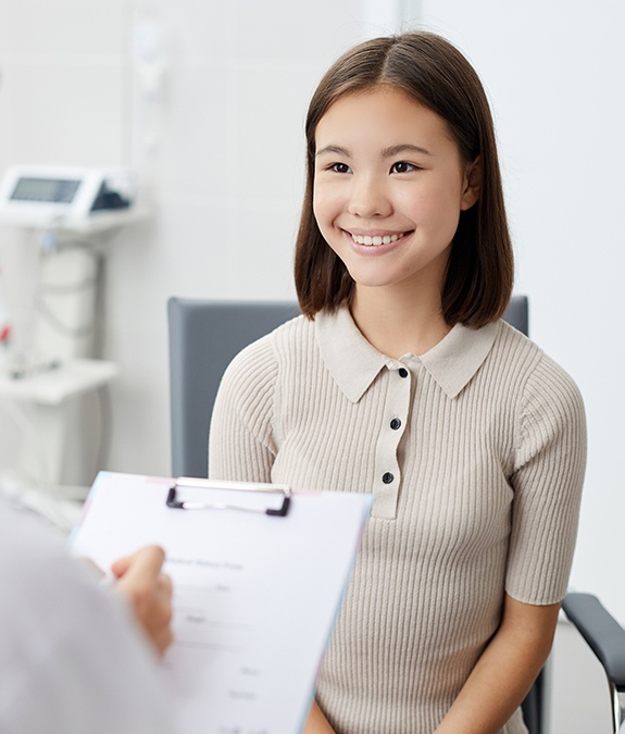 young preteen girl smiling at dentist during dental checkup