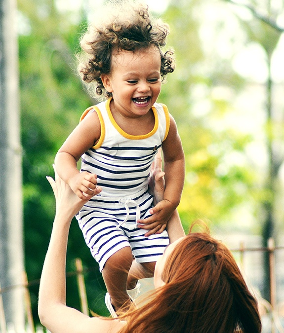 Mother tossing young son in air while he is laughing after tongue tie treatment