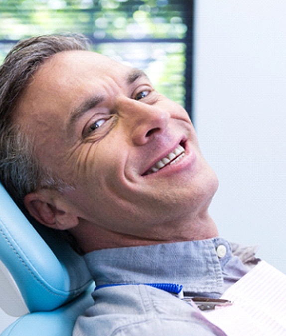 Man in blue shirt smiling in dental chair