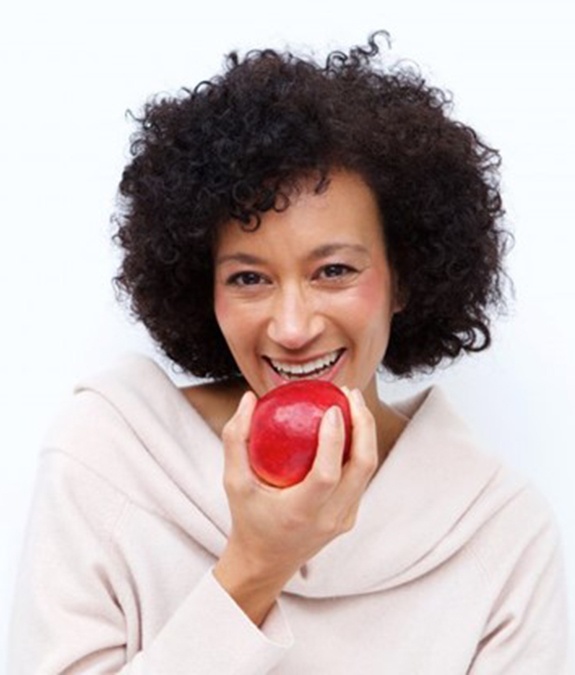 smiling woman biting into red apple 