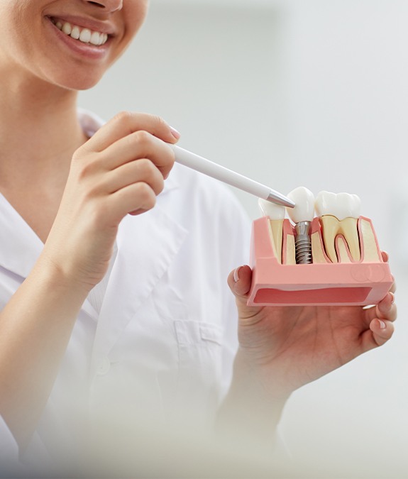 implant dentist in Mansfield holding a model of a jaw with a dental implant