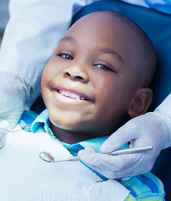 A young boy lying back in the dentist’s chair and preparing for an exam by a children’s dentist in Mansfield