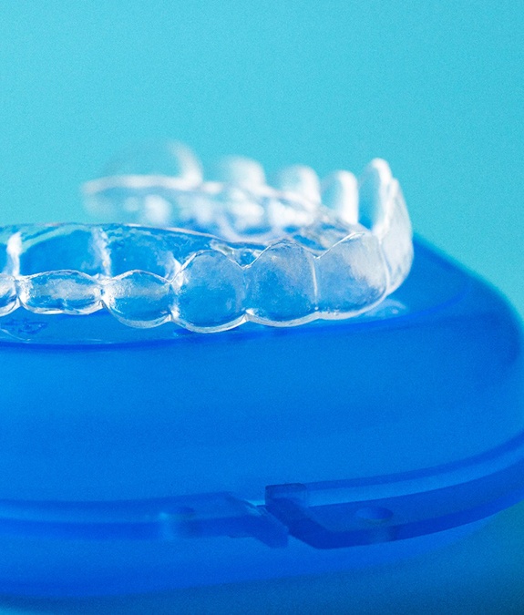 Clear aligner resting on top of blue storage case