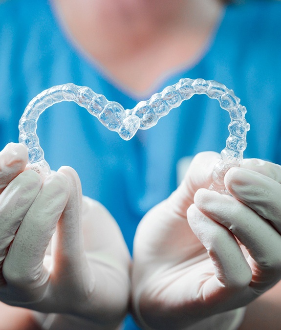 Dental team member using clear aligners to form heart shape