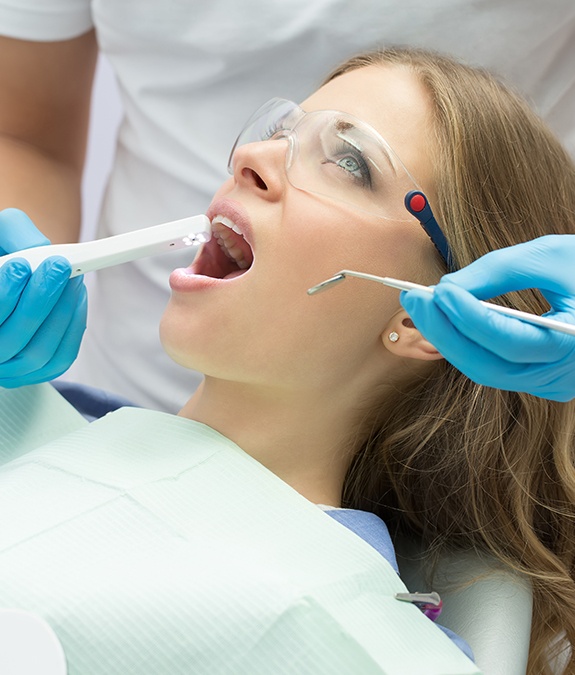 dentist using intraoral camera in woman's mouth