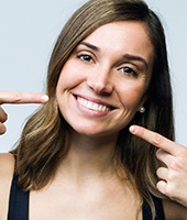 Woman pointing to her smile