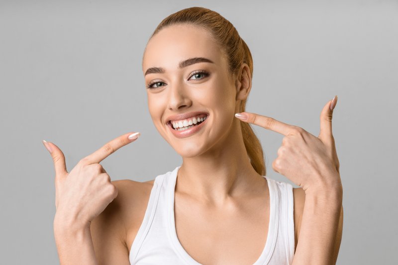 Woman smiling with teeth and pointing finger guns at both sides of her mouth